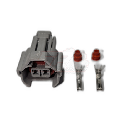 Grey 2-pin Denso High Guide injector connector housing with two metal terminals and red rubber seals shown separately