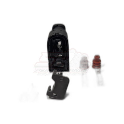 Toyota 2-pin Denso ignition coil connector exploded view showing black housing with internal contacts, detached black locking tab, clear terminal and red seal