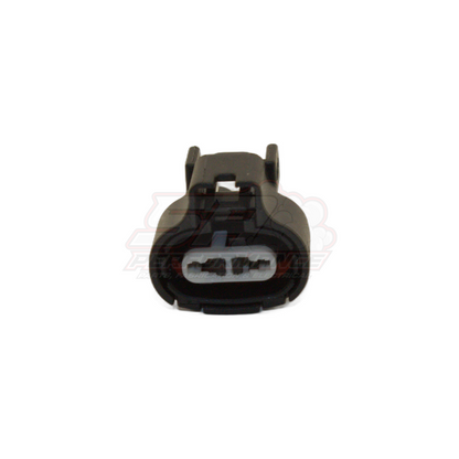 Black 2-pin Toyota Denso connector housing front view showing white terminal slots and locking tabs